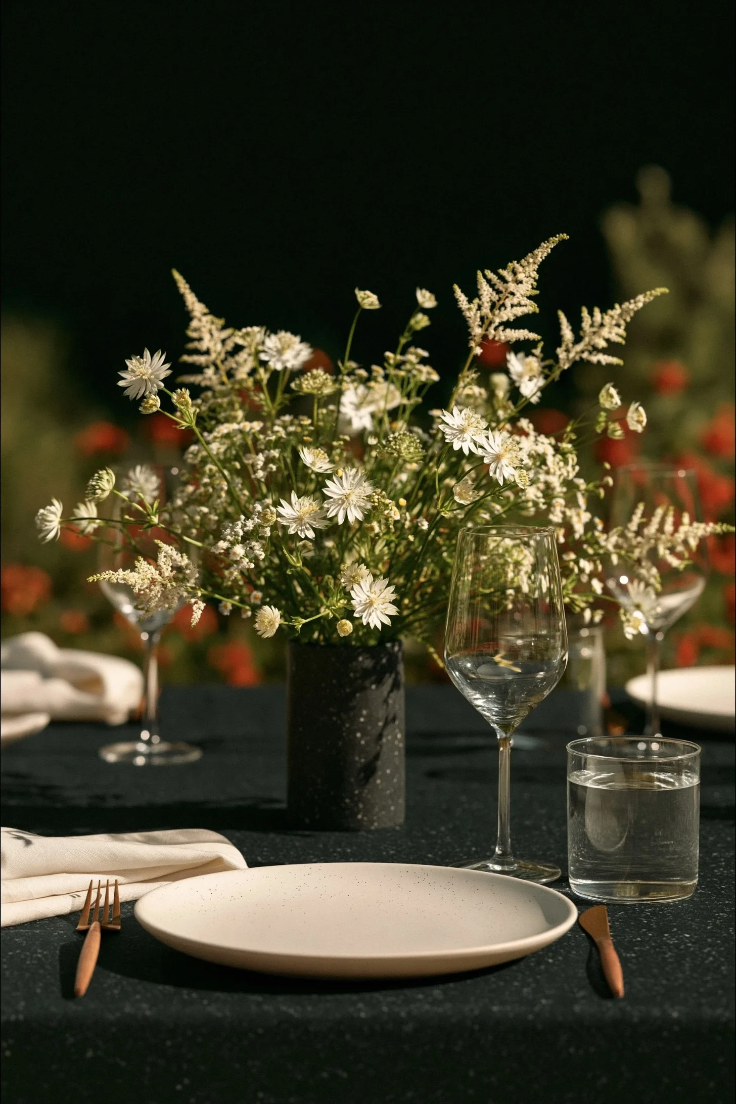 A forest green wedding tablescape layered with ferns, white daisies, glassware and taper candles