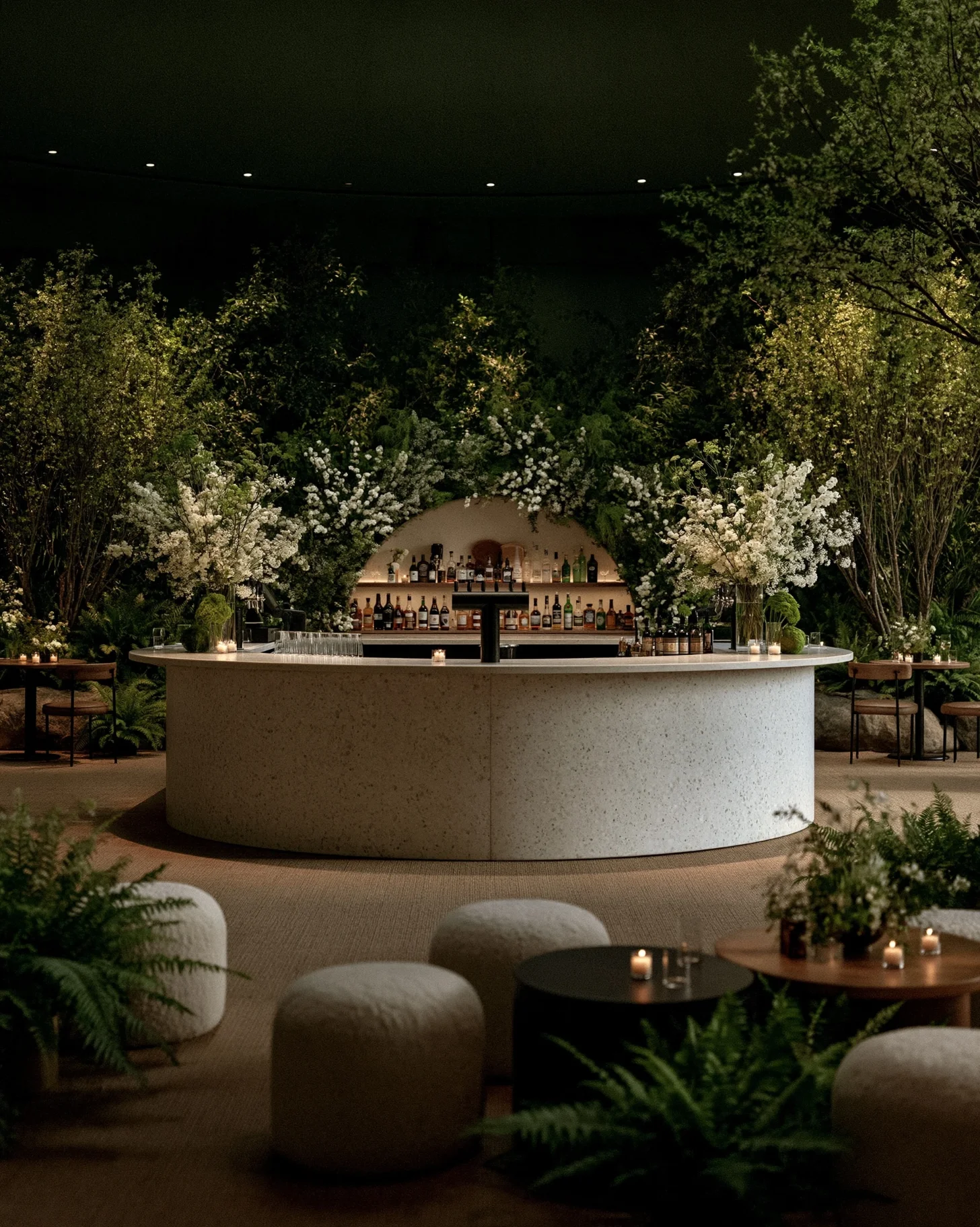 An oversized double-sided island wedding bar surrounded by greenery and lit with warm moody lighting