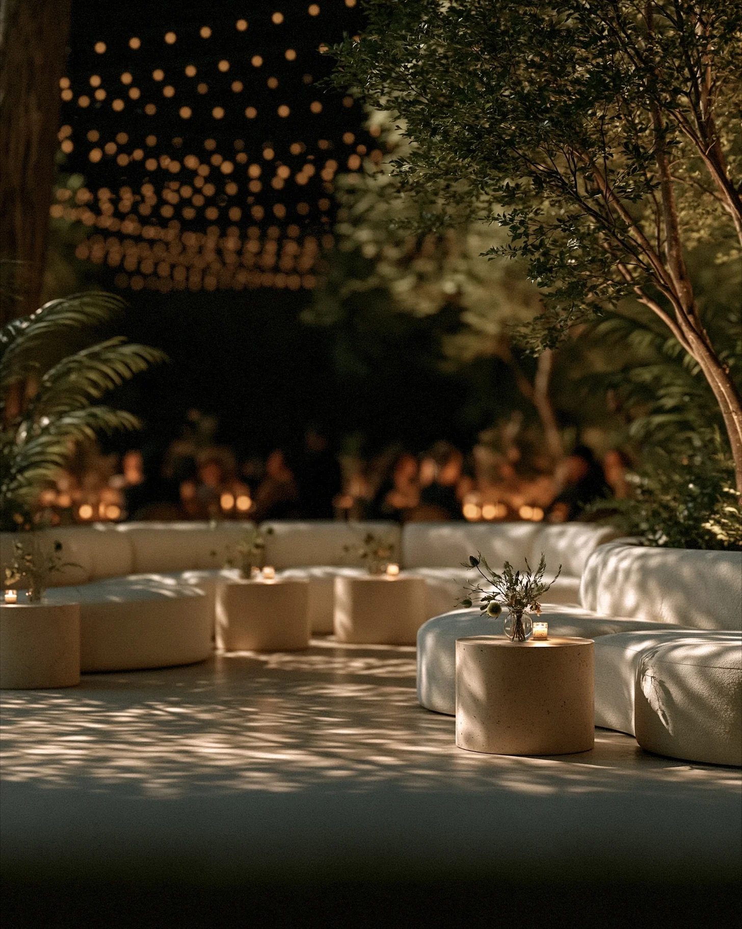 A wedding lounge staged on an open event floor with rental sofas, foliage and warm low lighting